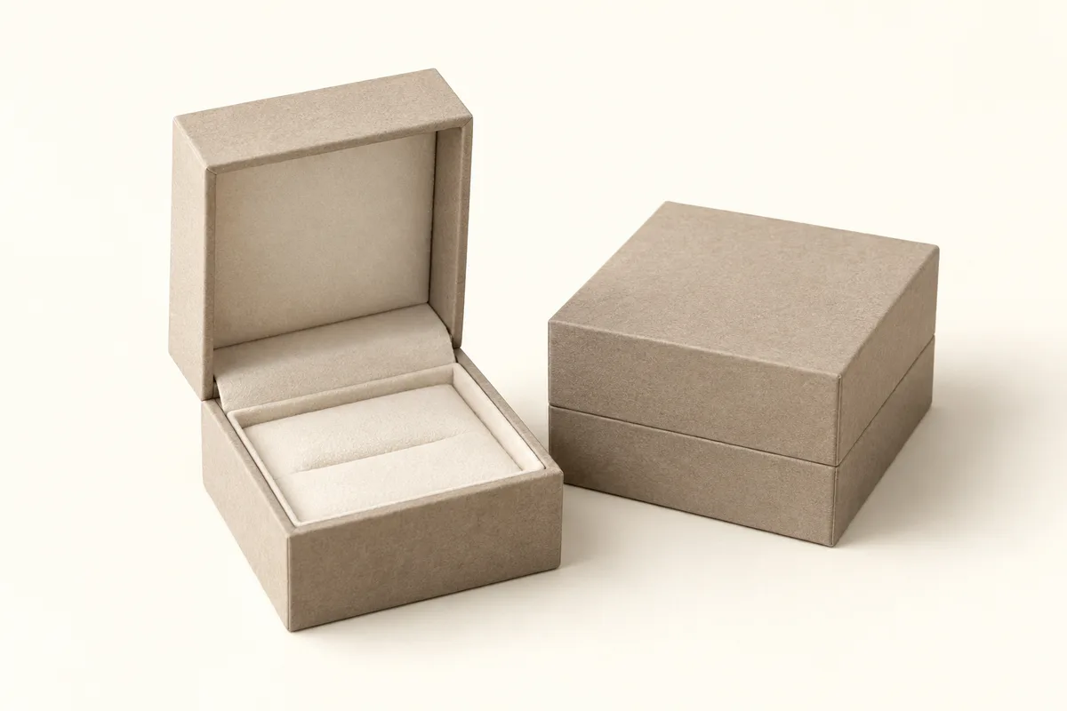 A small rigid jewelry box open to a cream insert, beside a closed one.